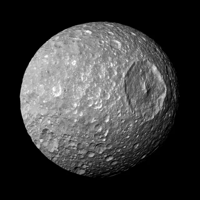 Mimas, una luna gris llena de cráteres con el enorme cráter Herschel a un lado, fotografiada por Cassini