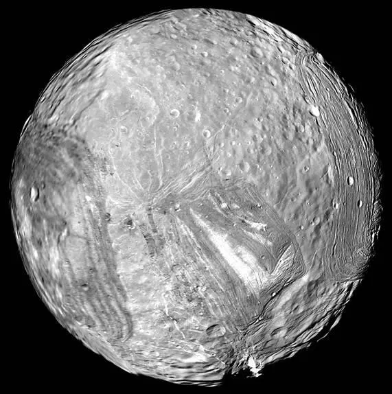 Miranda, una luna gris con zonas lisas y otras cruzadas por surcos y acantilados, fotografiada por la Voyager 2