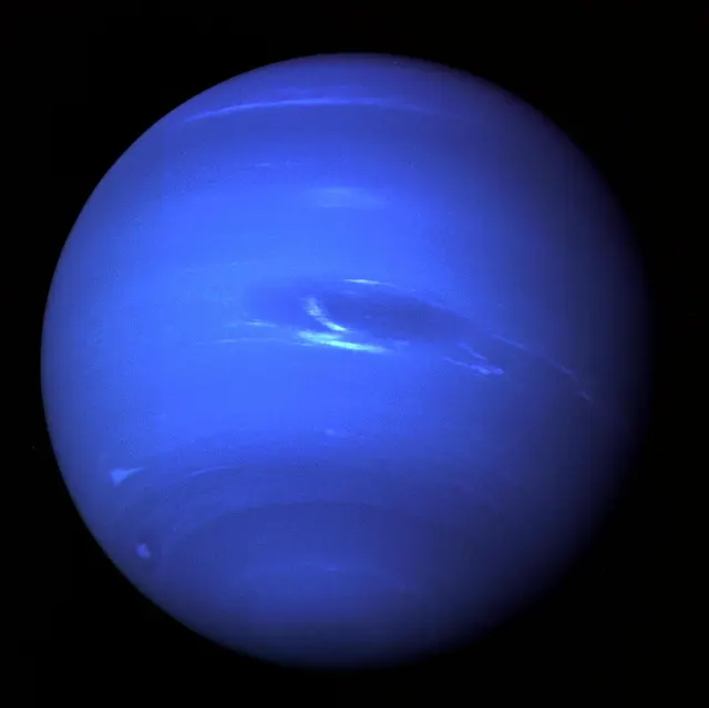 Neptuno, azul intenso con nubes blancas y manchas oscuras, fotografiado por la Voyager 2